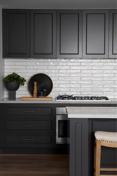 a kitchen with black cabinets and white subway backsplash