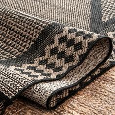 a black and white rug with fringes laying on top of the floor next to it