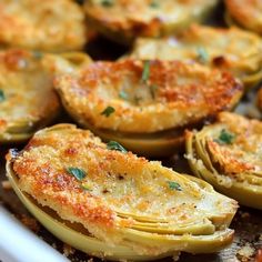 an assortment of baked food items in a baking dish, including artichokes