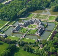 an aerial view of a large building in the middle of a green field with trees