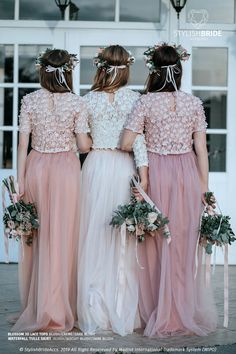 three bridesmaids in pink and white gowns with flowers on their head standing together