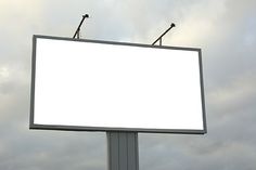 an empty billboard with two microphones on top in front of a cloudy blue sky