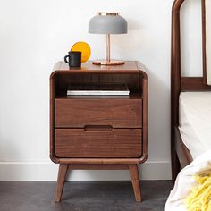 a bedside table with a lamp on it next to a bed and a yellow blanket