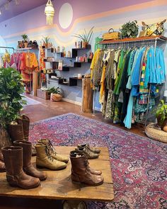 the inside of a clothing store with lots of shoes on display and plants in pots