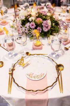 the table is set with pink and gold place settings