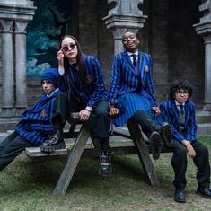 three people in blue and black striped suits sitting on a bench