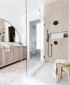 a bathroom with a walk in shower sitting next to a sink and a wooden stool