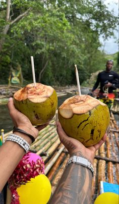 two people holding up coconuts with toothpicks in their hands on a bamboo raft