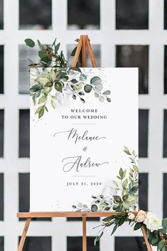 a welcome sign with greenery on it and the words welcome to our wedding written in white