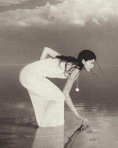 a woman is bending over in the water