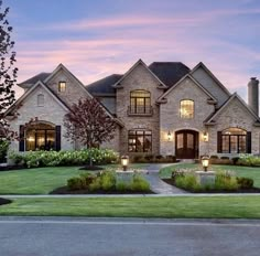 a large brick house with lots of windows and lights on it's front lawn