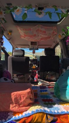 the back end of a van with colorful blankets and pillows on it's floor