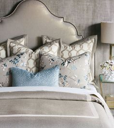 the bed has many pillows on it and is decorated with blue, white and grey flowers