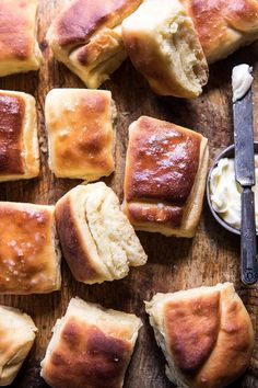 several pieces of bread on a wooden table next to butter and a knife with a spoon in it