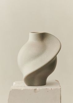 a white vase sitting on top of a wooden block