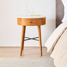 a small table with two glasses on it next to a bed