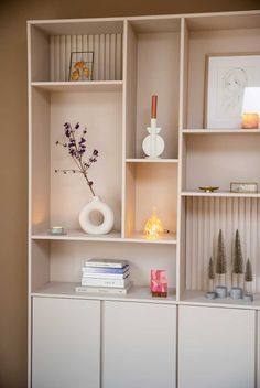 a white shelf filled with lots of books and vases on top of it's shelves