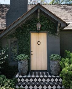 a house with two large planters in front of it and a checkered floor