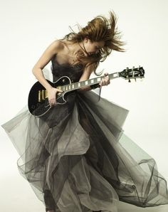 a woman in a long dress holding a guitar