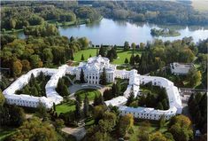 an aerial view of a large white building in the middle of some trees and water