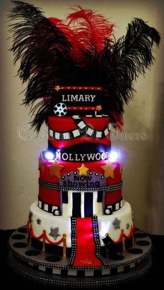 a three tiered cake decorated with red, white and black decorations is lit up