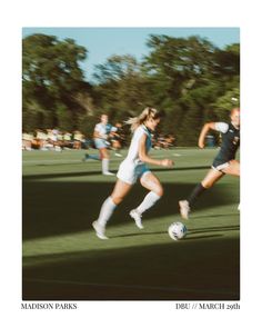 the girls are playing soccer on the field with trees in the backgrouds