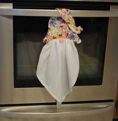 a white towel hanging from the handle of an oven door with floral print on it