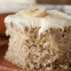 a close up of a banana cake on a plate with frosting and sliced bananas