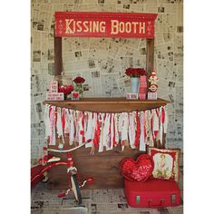 a red and white valentine's day display with a kissing booth sign on the wall