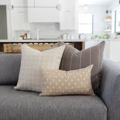 a couch with pillows on it in front of an open kitchen and living room area