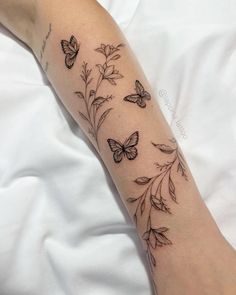 a woman's arm with butterflies on it and flowers in the middle of her arm