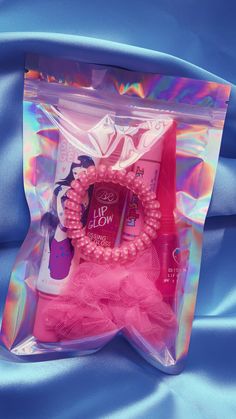 the package is packed with pink items on blue satin material, including bracelets and hair clips