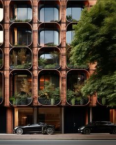 an unusual building with many windows and plants on the outside, as well as cars parked in front