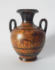 an old vase with designs on it sitting on a white surface, against a plain background