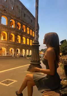 a woman is sitting on a bench in front of the colossion