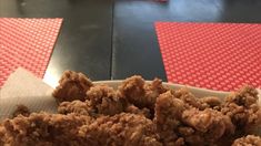 a plate full of fried food sitting on top of a red and black tablecloth