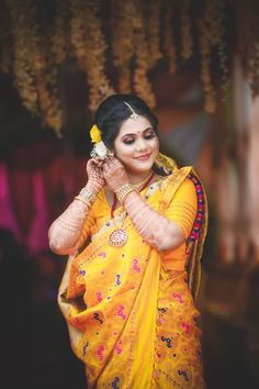 a woman in yellow sari holding her hands to her face and smiling at the camera