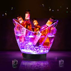 an illuminated ice bucket filled with bottles of wine and ice cubes on a table