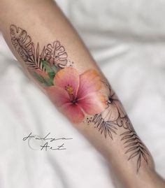 a woman's leg with flowers and leaves tattooed on the side of her arm