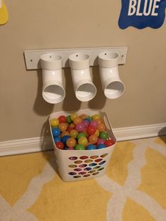 a bucket filled with lots of gumballs on top of a floor next to a wall