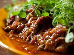 a yellow plate topped with meat and greens