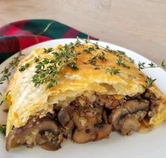 a mushroom and cheese quiche on a white plate with a green garnish