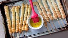 several skewers are being prepared on a baking sheet with a red spatula