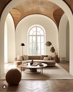 a living room filled with furniture next to a large arched window and wooden flooring