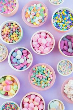 small bowls filled with candy and sprinkles on a purple tablecloth,