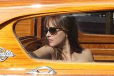 a woman in sunglasses is looking out the window of an old car with wood trim