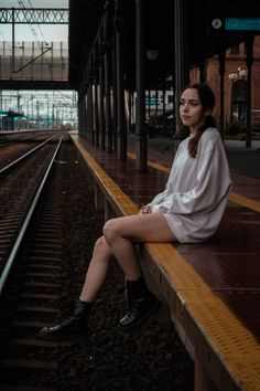 a woman is sitting on the train tracks