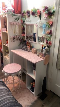 a vanity with stools and flowers on the wall in a small room next to a bed