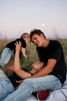 a man holding a baby while laying on the ground