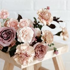 a bouquet of pink flowers sitting on top of a wooden table next to a brick wall